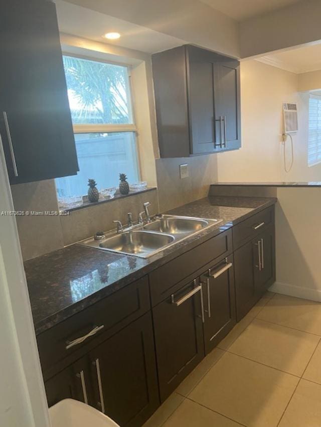 kitchen with dark stone countertops, a wall mounted AC, sink, and light tile patterned floors