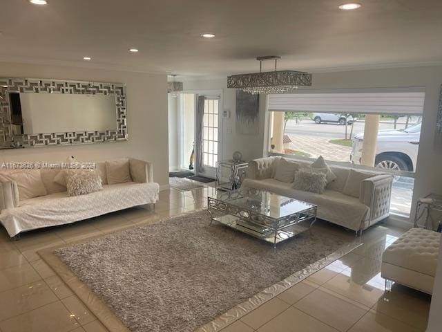 living room featuring tile patterned floors, ornamental molding, and a chandelier