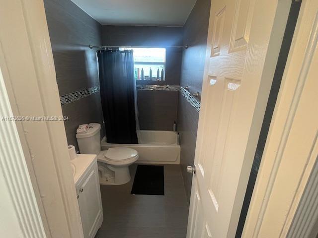 full bathroom with vanity, shower / tub combo, and toilet