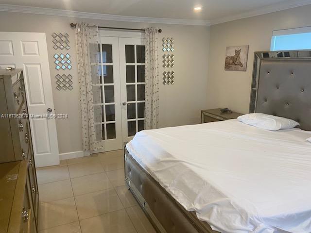 bedroom featuring french doors, ornamental molding, and light tile patterned floors