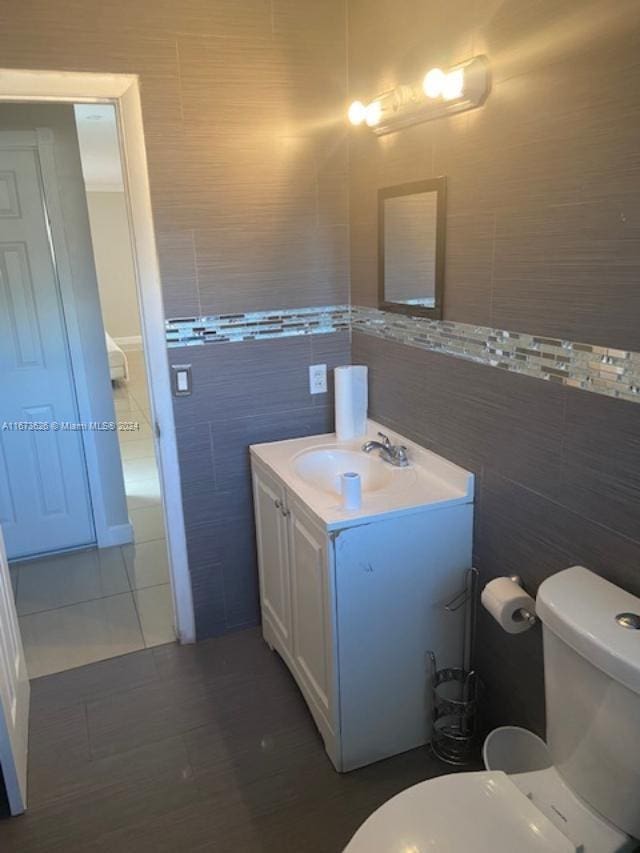 bathroom with vanity, toilet, and tile walls