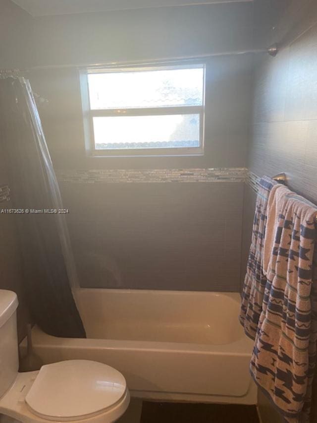 bathroom featuring toilet, plenty of natural light, and shower / tub combo