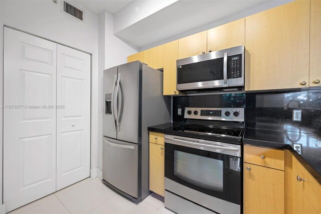 kitchen with decorative backsplash, range hood, light brown cabinets, stainless steel appliances, and light tile patterned floors