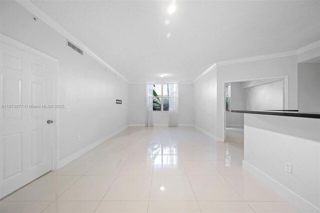 tiled empty room featuring ornamental molding