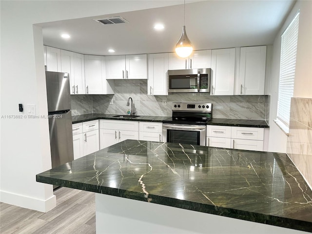 kitchen featuring sink, kitchen peninsula, light hardwood / wood-style flooring, white cabinetry, and appliances with stainless steel finishes