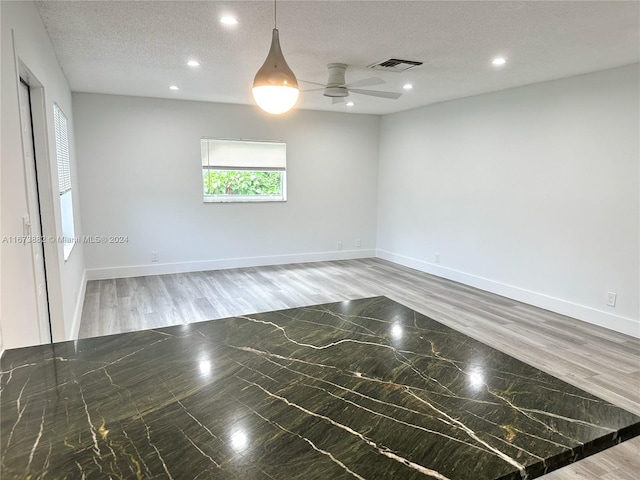 empty room with ceiling fan, hardwood / wood-style flooring, and a textured ceiling