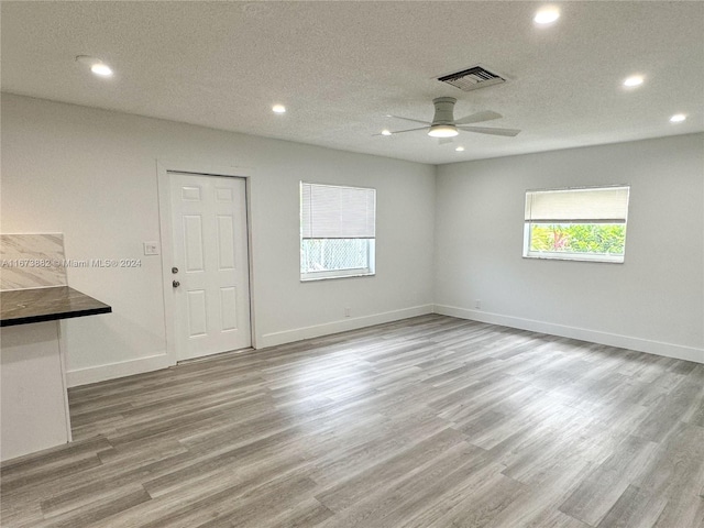 spare room featuring a textured ceiling, ceiling fan, and light hardwood / wood-style flooring