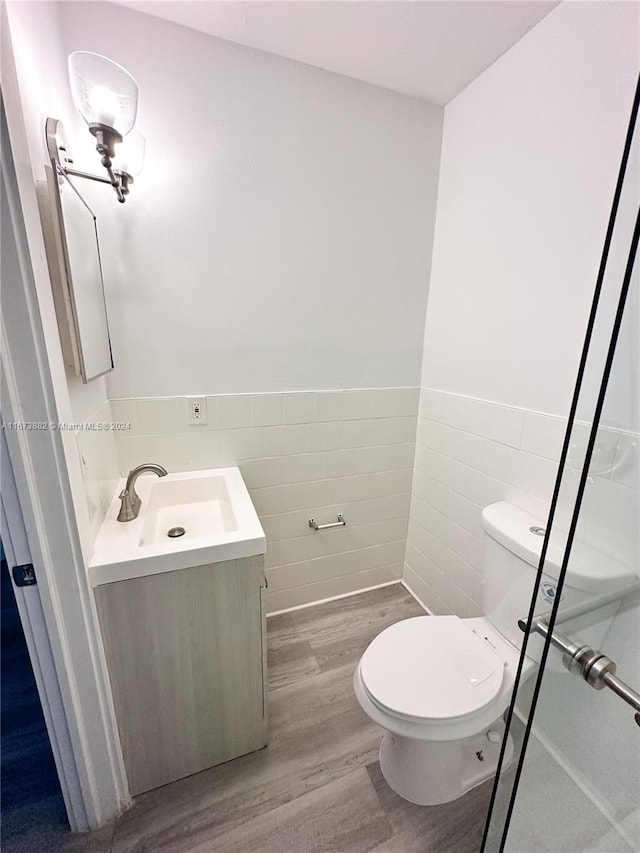 bathroom featuring toilet, tile walls, vanity, and wood-type flooring