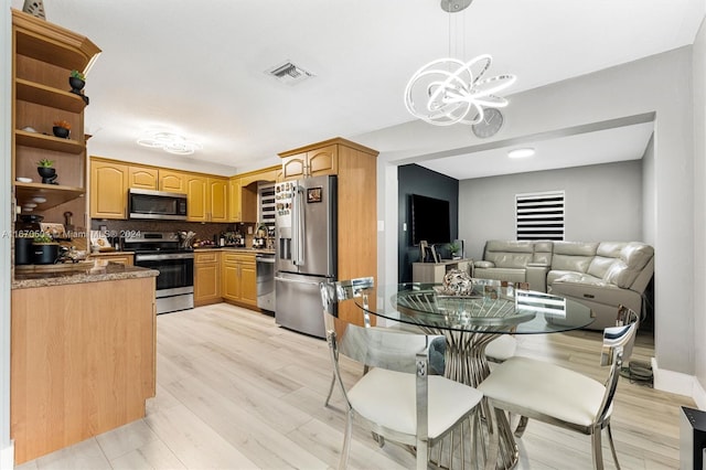 kitchen with an inviting chandelier, tasteful backsplash, light hardwood / wood-style flooring, decorative light fixtures, and stainless steel appliances