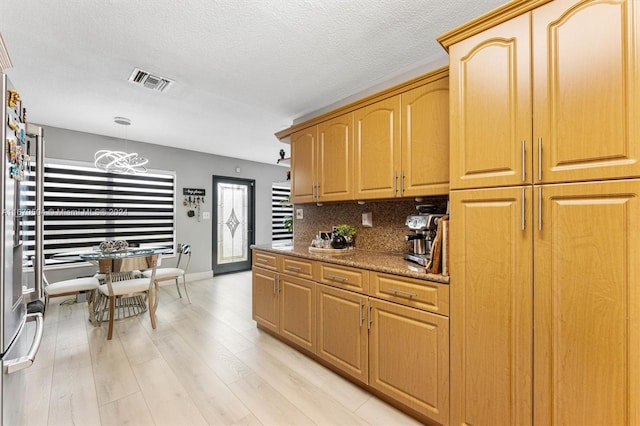 kitchen featuring light wood-type flooring, pendant lighting, a chandelier, and tasteful backsplash