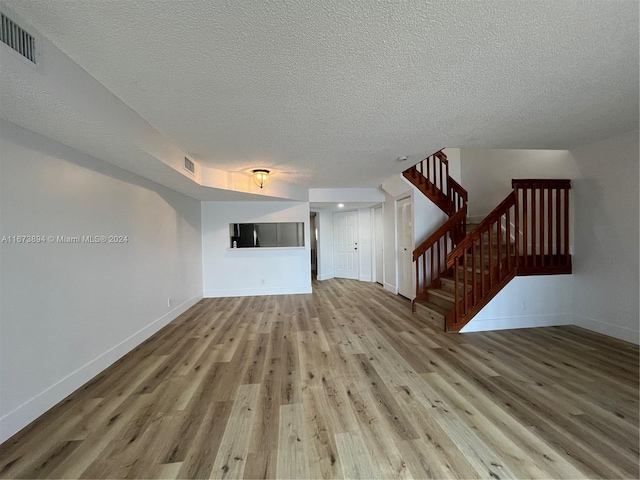 unfurnished living room with a textured ceiling and light wood-type flooring