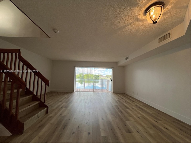 unfurnished living room with a textured ceiling and hardwood / wood-style flooring