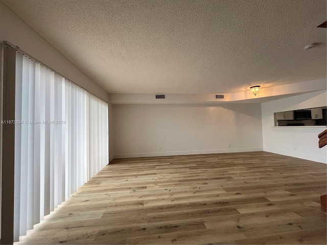 spare room featuring hardwood / wood-style flooring and a textured ceiling