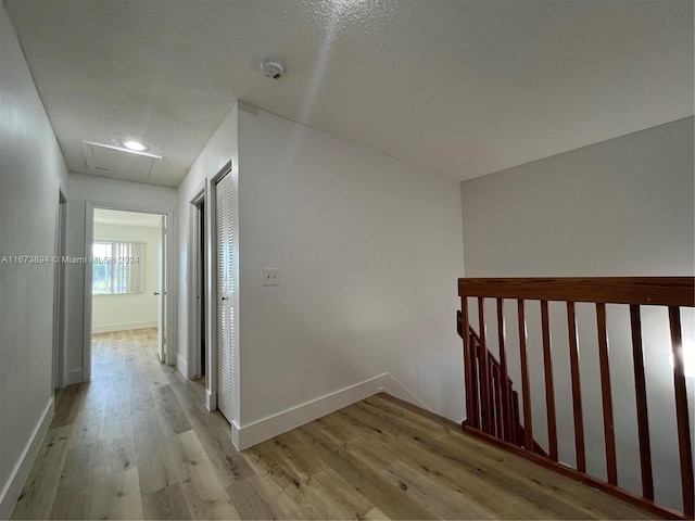 hallway featuring a textured ceiling and light hardwood / wood-style flooring