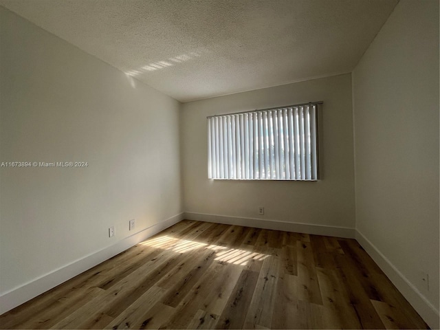 unfurnished room with wood-type flooring and a textured ceiling