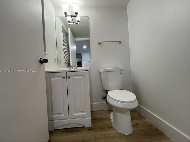 bathroom with hardwood / wood-style floors, vanity, toilet, and a chandelier