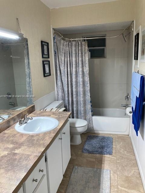 bathroom featuring toilet, tile patterned flooring, shower / bath combo with shower curtain, and vanity