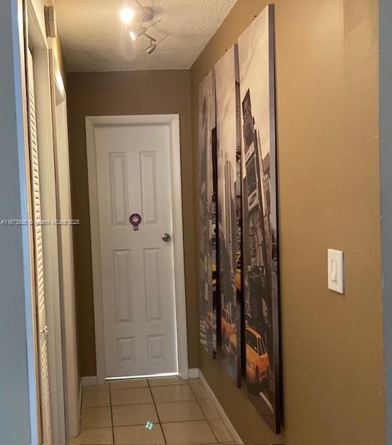 entryway with a textured ceiling, tile patterned flooring, and baseboards