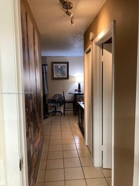 hallway featuring light tile patterned floors and a textured ceiling