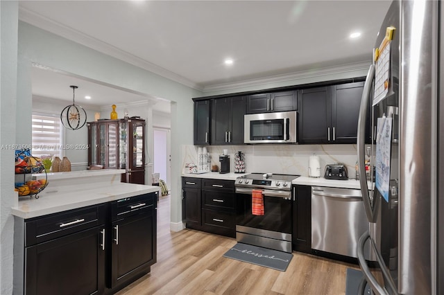 kitchen featuring hanging light fixtures, backsplash, stainless steel appliances, crown molding, and light hardwood / wood-style floors