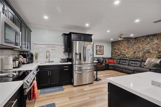 kitchen featuring crown molding, light hardwood / wood-style flooring, sink, stainless steel appliances, and backsplash