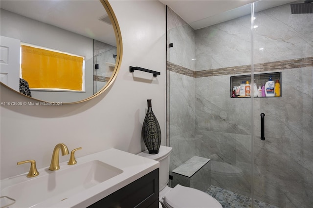 bathroom featuring vanity, a shower with door, and toilet