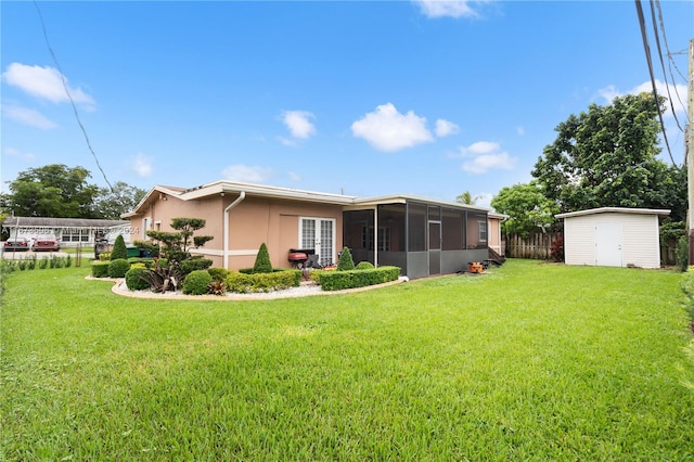 rear view of property featuring a yard, a sunroom, and a storage unit