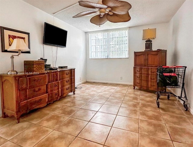 living area featuring ceiling fan, light tile patterned floors, and a textured ceiling