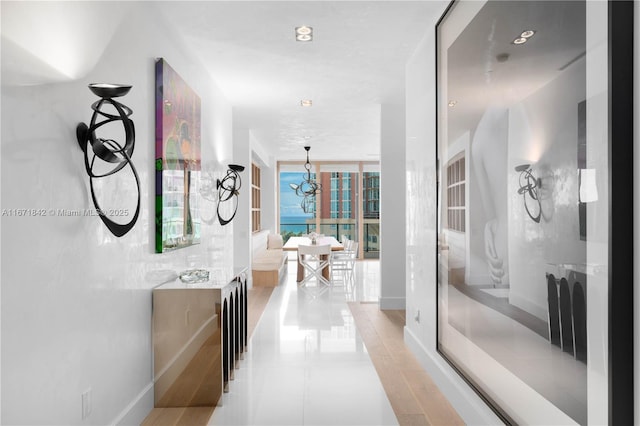 hall with light tile patterned floors, expansive windows, and a notable chandelier