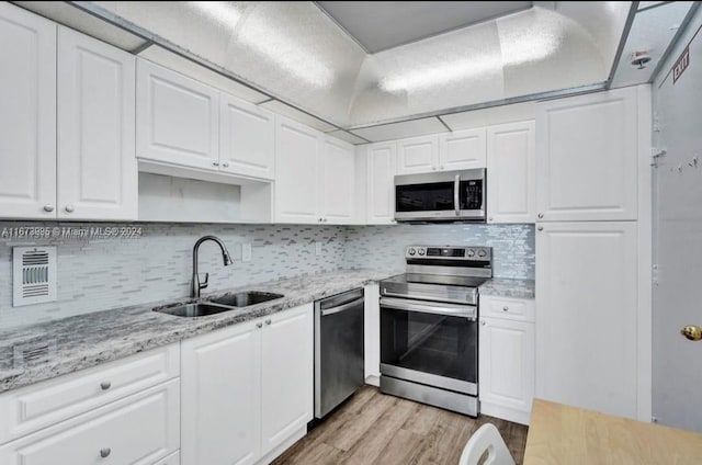 3801 S Ocean Dr Unit 9W, Hollywood, FL 33019 - kitchen with white cabinets, a sink, light wood-style floors, stainless steel appliances, and tasteful backsplash