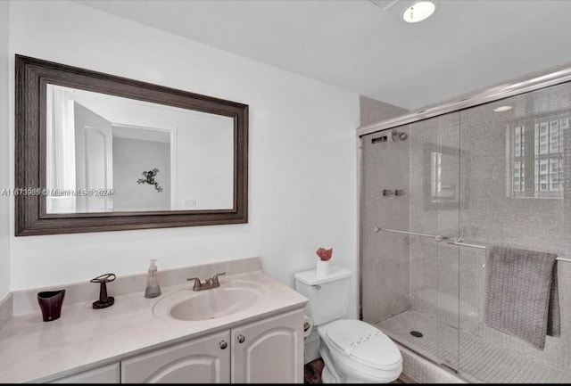 bathroom with vanity, a shower with door, and toilet