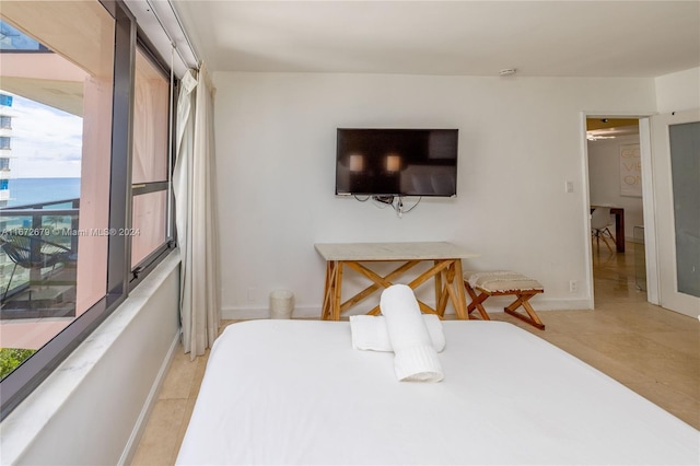 bedroom with light tile patterned floors and a water view