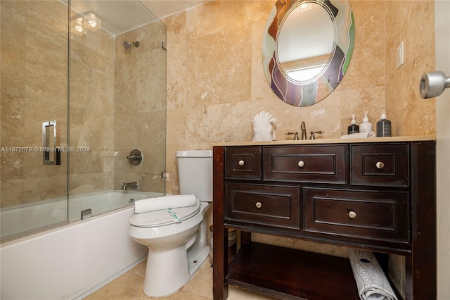 full bathroom featuring vanity, bath / shower combo with glass door, tile walls, tile patterned floors, and toilet