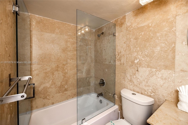 full bathroom featuring vanity, tile walls, toilet, and tiled shower / bath combo