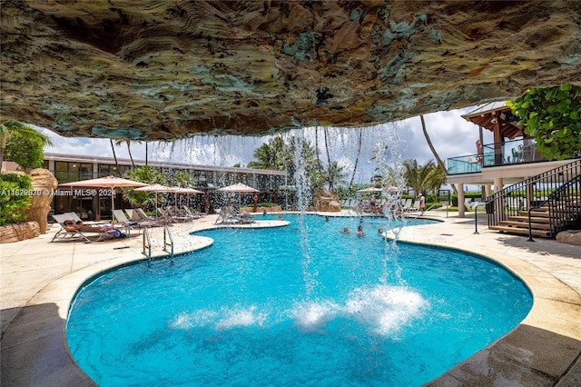 view of swimming pool with pool water feature and a patio area