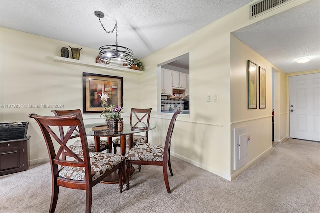 dining area featuring light carpet, a textured ceiling, and a chandelier