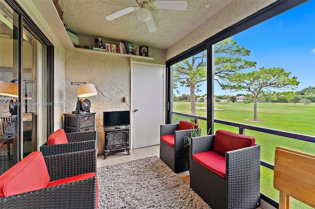 sunroom with a wood stove and ceiling fan