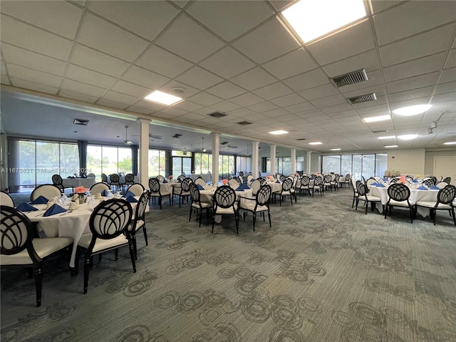 carpeted dining room with a drop ceiling and ornate columns