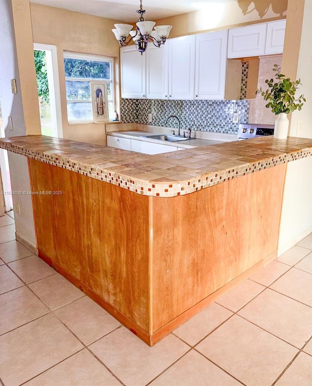 kitchen with sink, tasteful backsplash, white cabinets, light tile patterned flooring, and kitchen peninsula