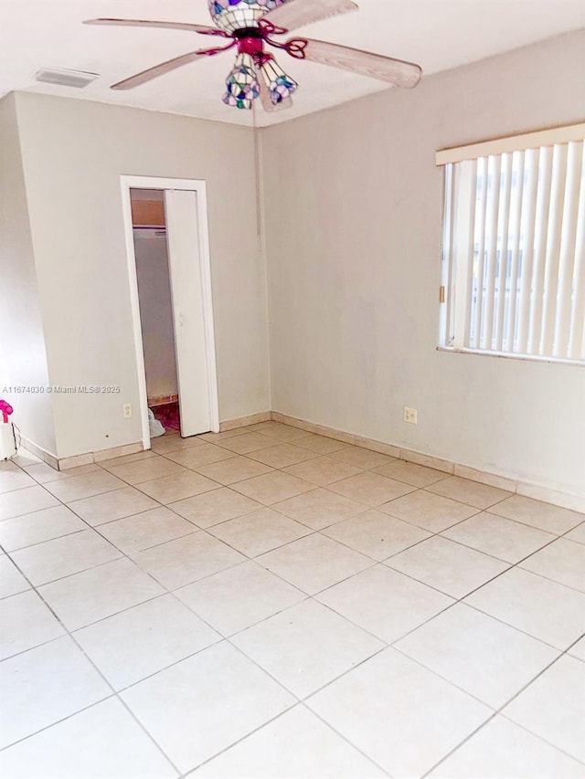 tiled spare room with ceiling fan