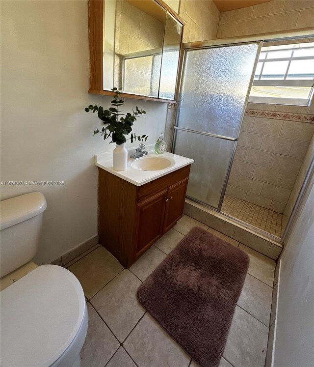 bathroom with tile patterned floors, toilet, an enclosed shower, and vanity