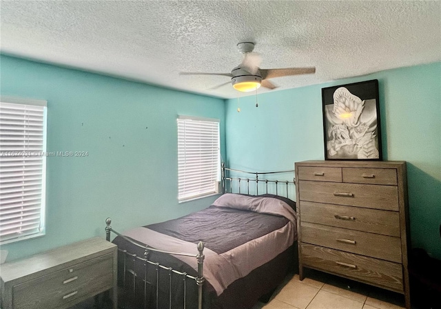 tiled bedroom with ceiling fan and a textured ceiling