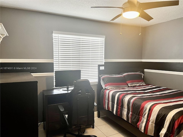 bedroom with ceiling fan, light tile patterned floors, and a textured ceiling