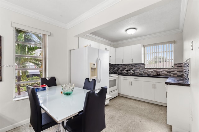 kitchen with white cabinets, decorative backsplash, white appliances, and plenty of natural light