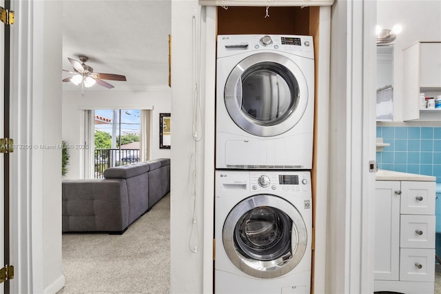 laundry room featuring ceiling fan and stacked washer / dryer