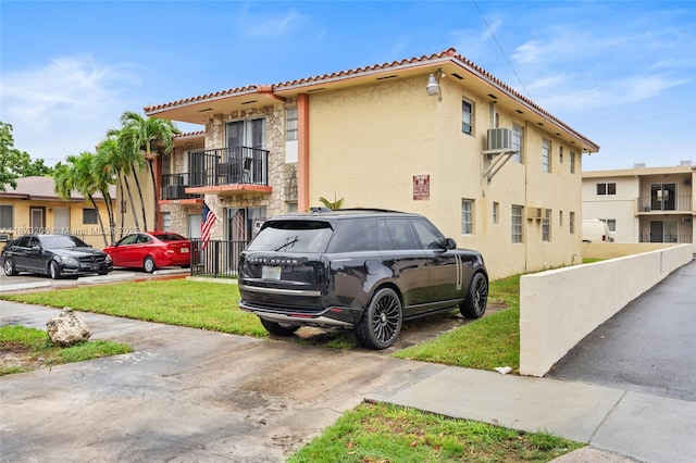 view of side of home featuring a lawn and a balcony