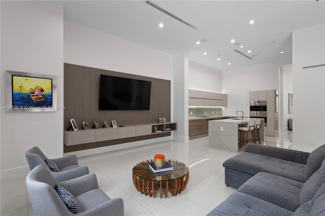 tiled living room featuring sink and a high ceiling