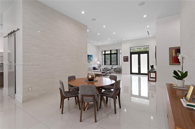 tiled dining room with french doors, a barn door, and tile walls