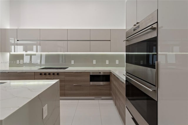 kitchen featuring white cabinetry, black electric cooktop, double oven, light stone countertops, and backsplash