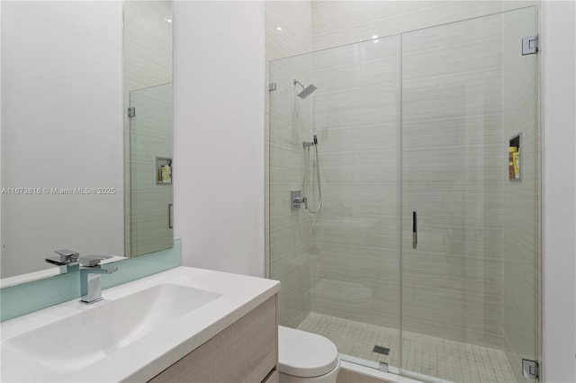 bathroom with a shower with door, vanity, and toilet